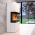 A modern white corner fireplace with a visible orange fire, set in a contemporary living room with a gray concrete wall, light wood floors, a patterned rug, and a dark leather sofa.