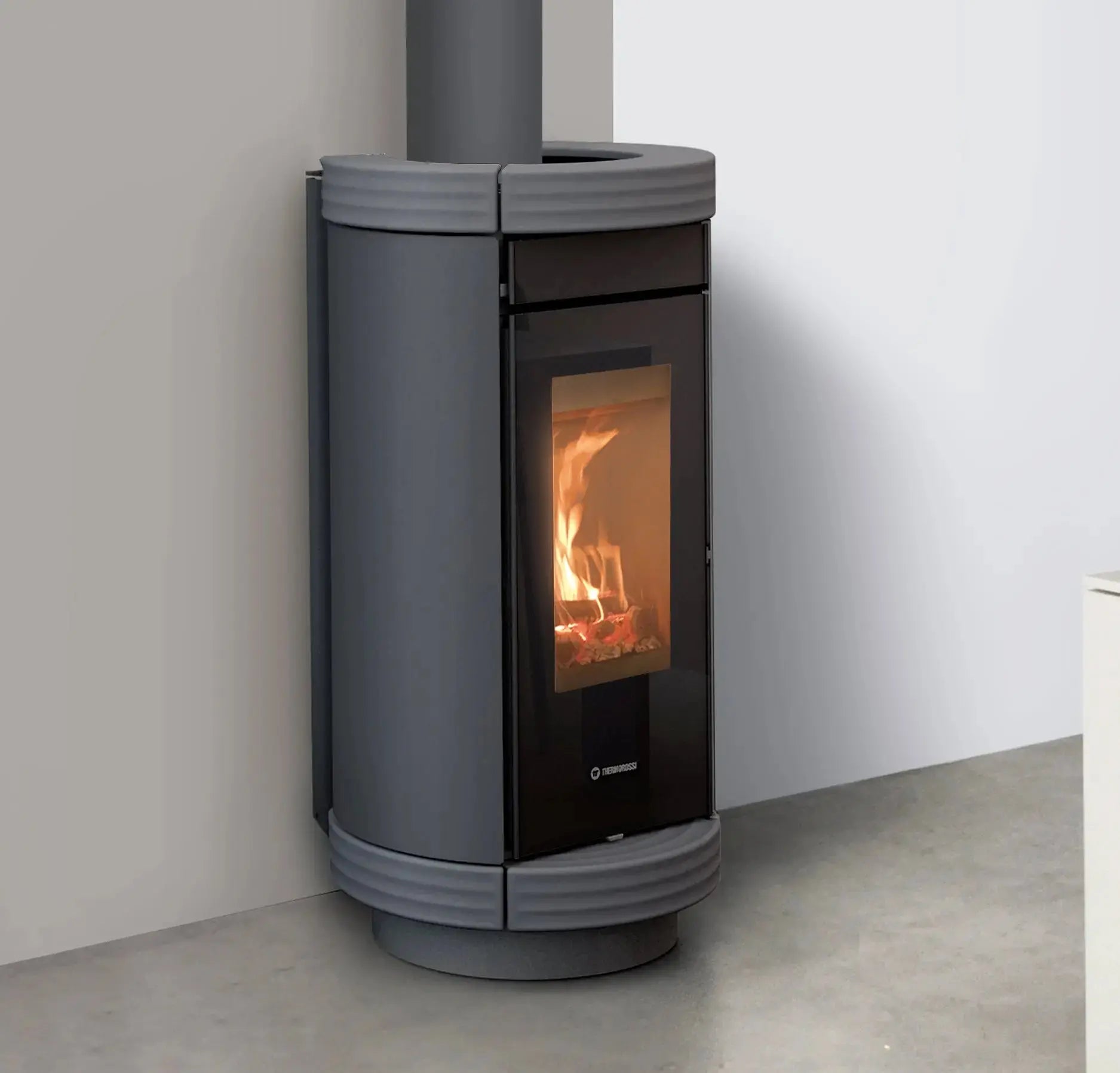 Modern gray pellet stove with visible flames inside, mounted on a wall.