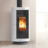 A modern wood-burning stove with a white ribbed ceramic body, black glass door, and visible orange fire, set against a neutral beige wall and light wood floor.
