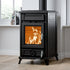 A black wood-burning stove with an open door showing a warm orange fire inside, set in a room with light wood floors and a white wall.