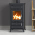 A black metal wood-burning stove with a visible orange fire inside, set against a dark gray wall and light floor. A small wooden shelf is partially visible on the right side.