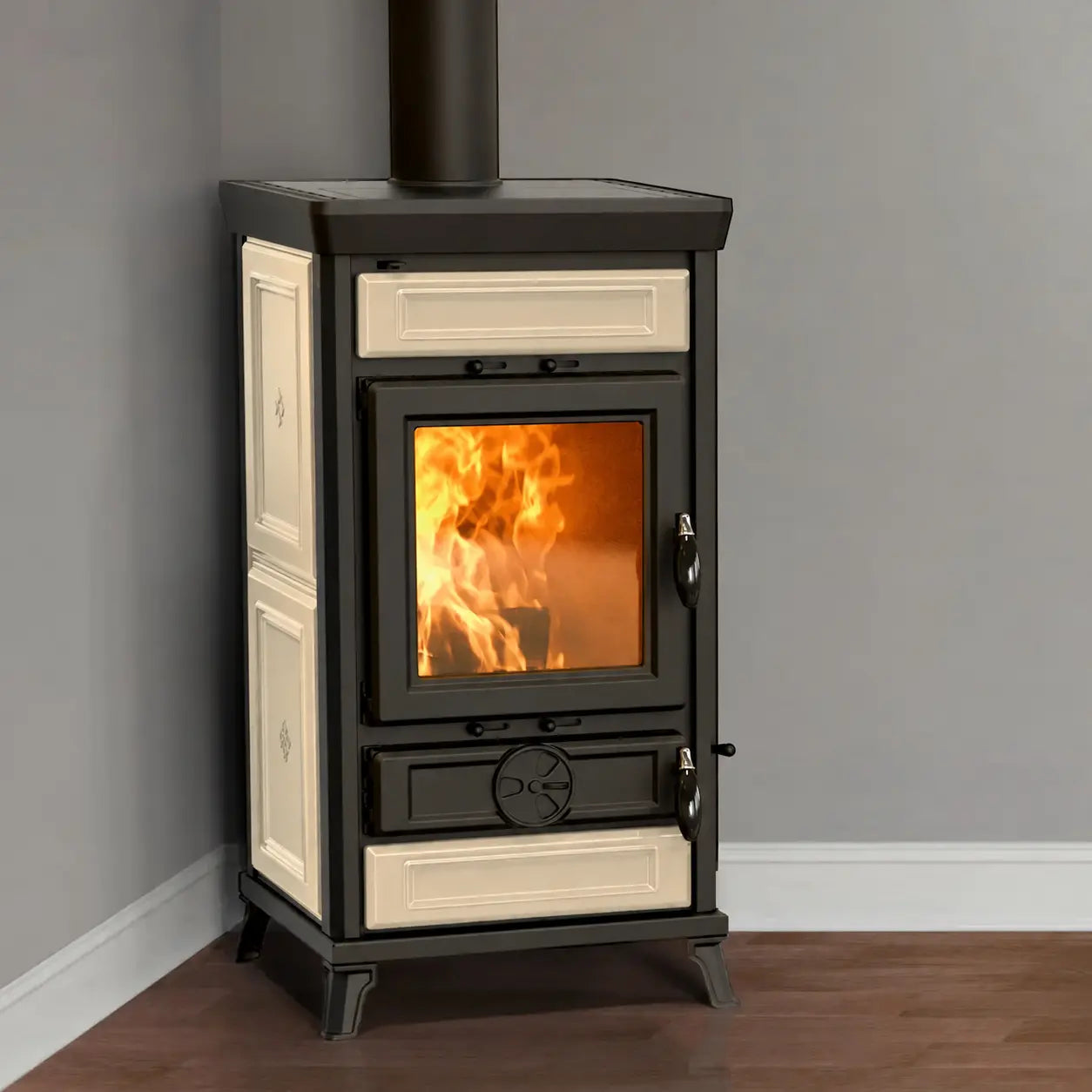 A freestanding black and cream wood-burning stove with a visible fire inside, photographed in a room corner with gray walls and a wood floor.