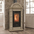 A freestanding wood-burning stove with a down colored ornate frame and a black glass front door showing a glowing fire, set against a stone wall in a room with wood floors and a white door.