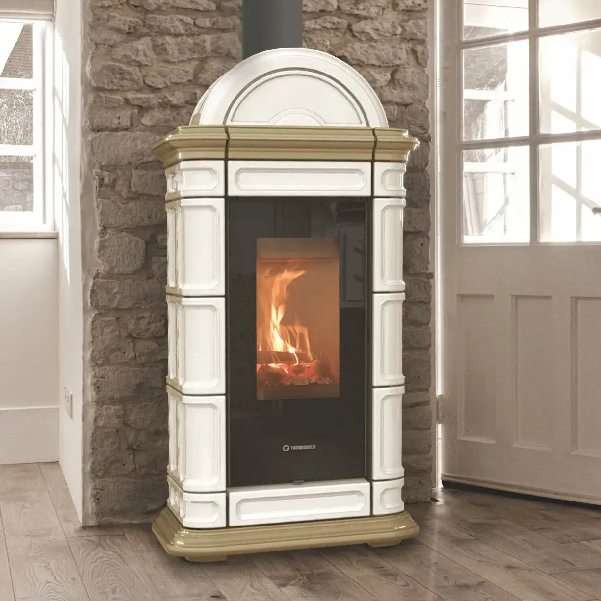 A freestanding wood-burning stove with a white and gold painted frame, set against a stone wall in a room with wood flooring and a white door.
