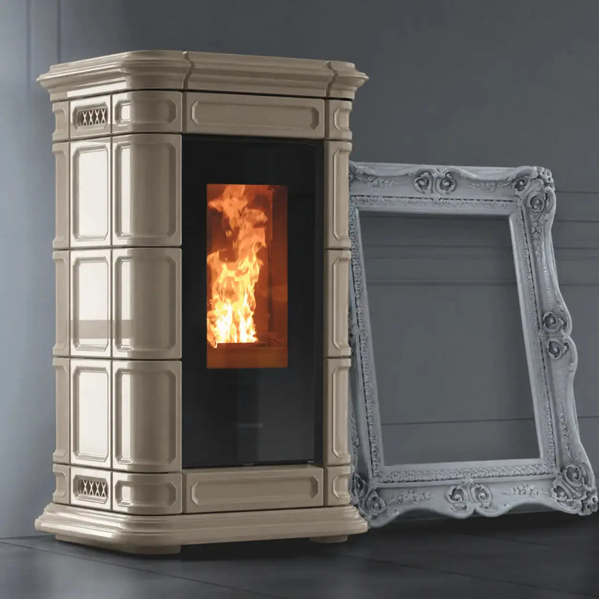 A cream-colored wood-burning stove with a black glass door showing a fire, positioned next to an ornate white picture frame against a dark gray wall.